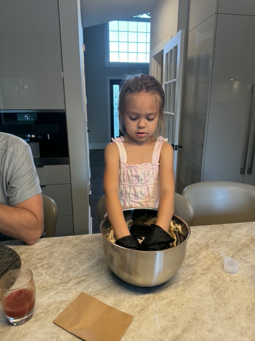 A small girl mixing Everything dough by hand in a steel bowl